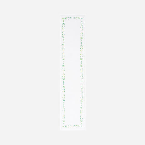 Full-length embroidered table runner featuring green floral vine motifs on a white cotton base displayed on a plain background