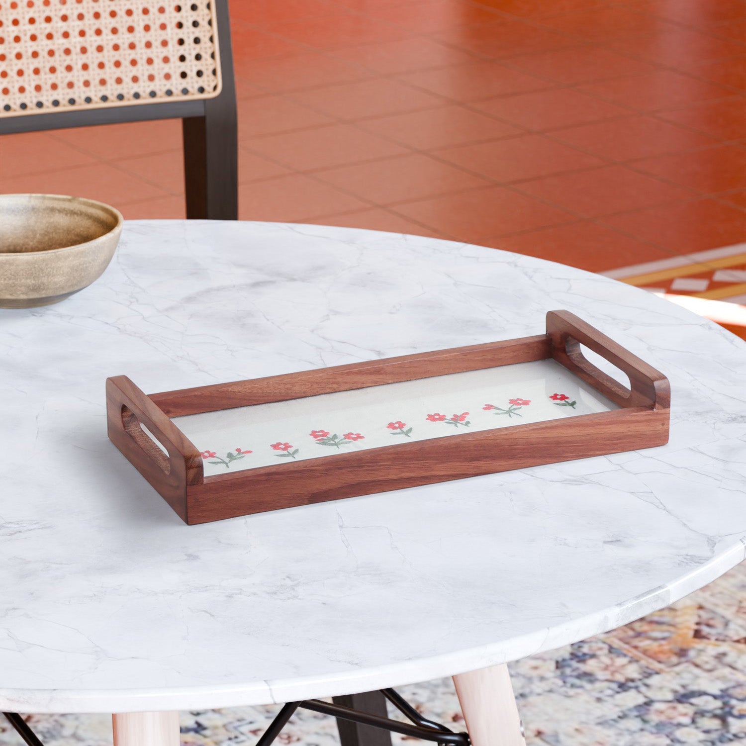 Hand embroidered wooden serving tray with pink floral motifs and green leaves on white fabric, styled with tea cups and snacks on a tabletop