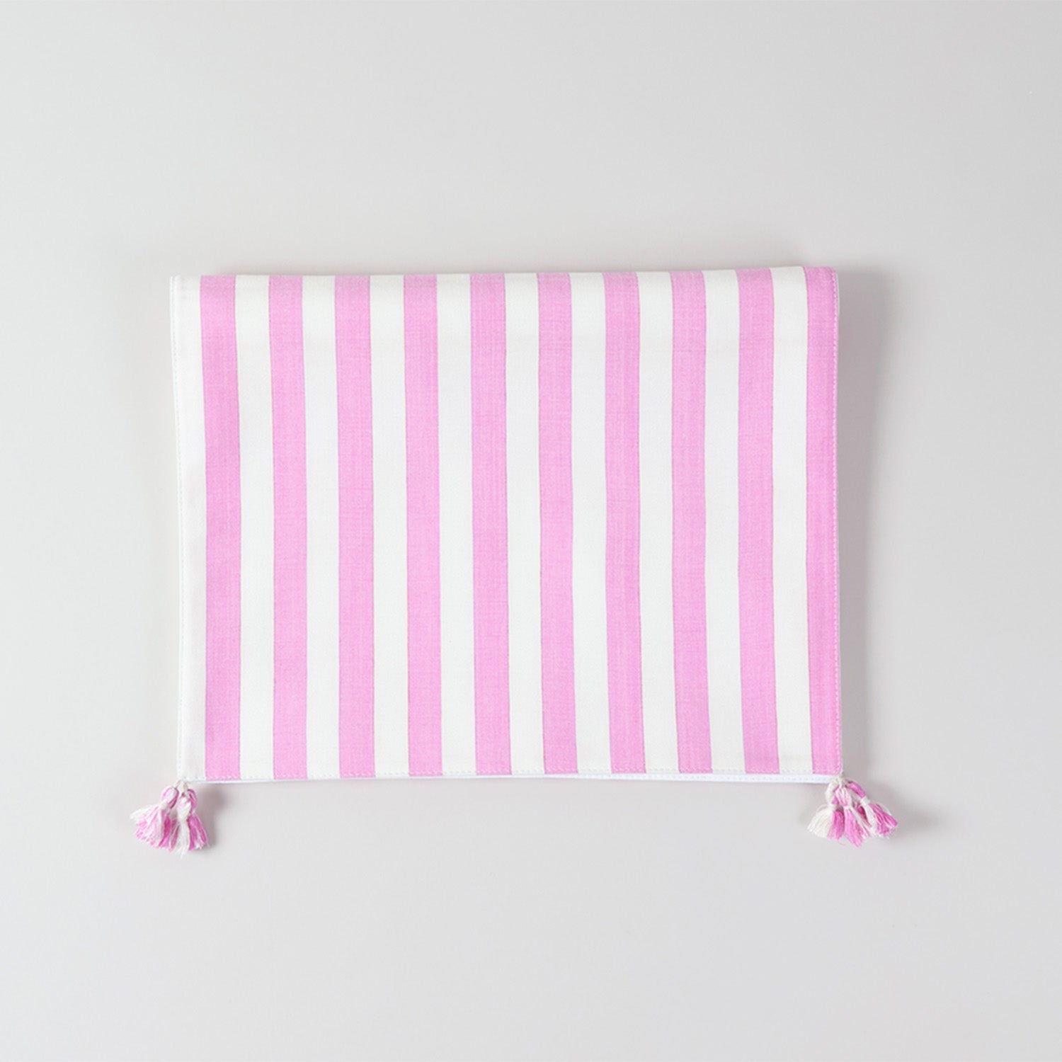 Folded cotton table runner showcasing white and pink woven stripes, handcrafted texture, and decorative tassels