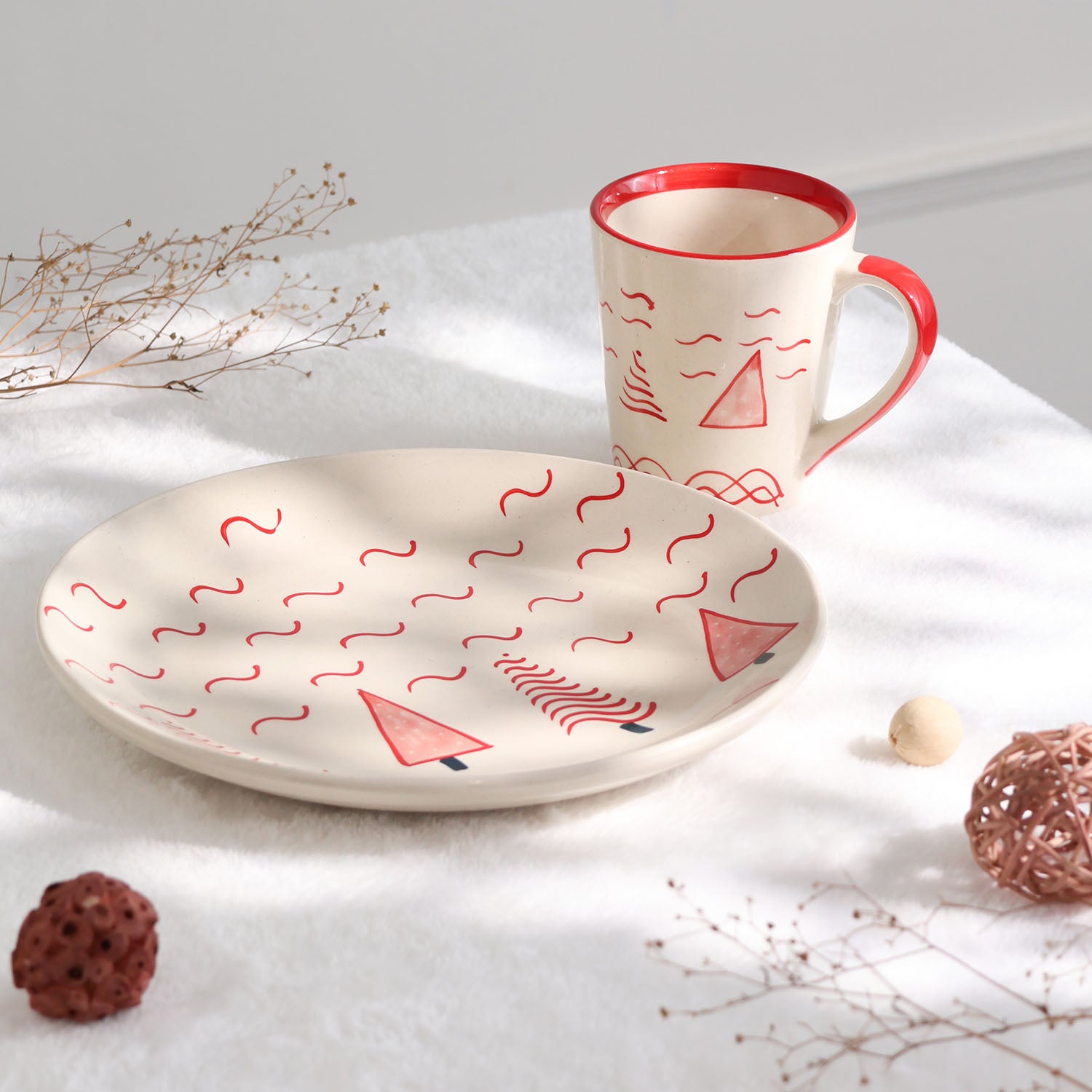 White and red Christmas tree ceramic breakfast set featuring a hand-painted plate and mug styled  on a festive table setting