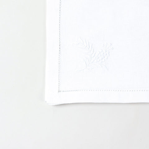 Detailed corner view of a handcrafted white cotton table runner featuring delicate wild floral chikankari embroidery