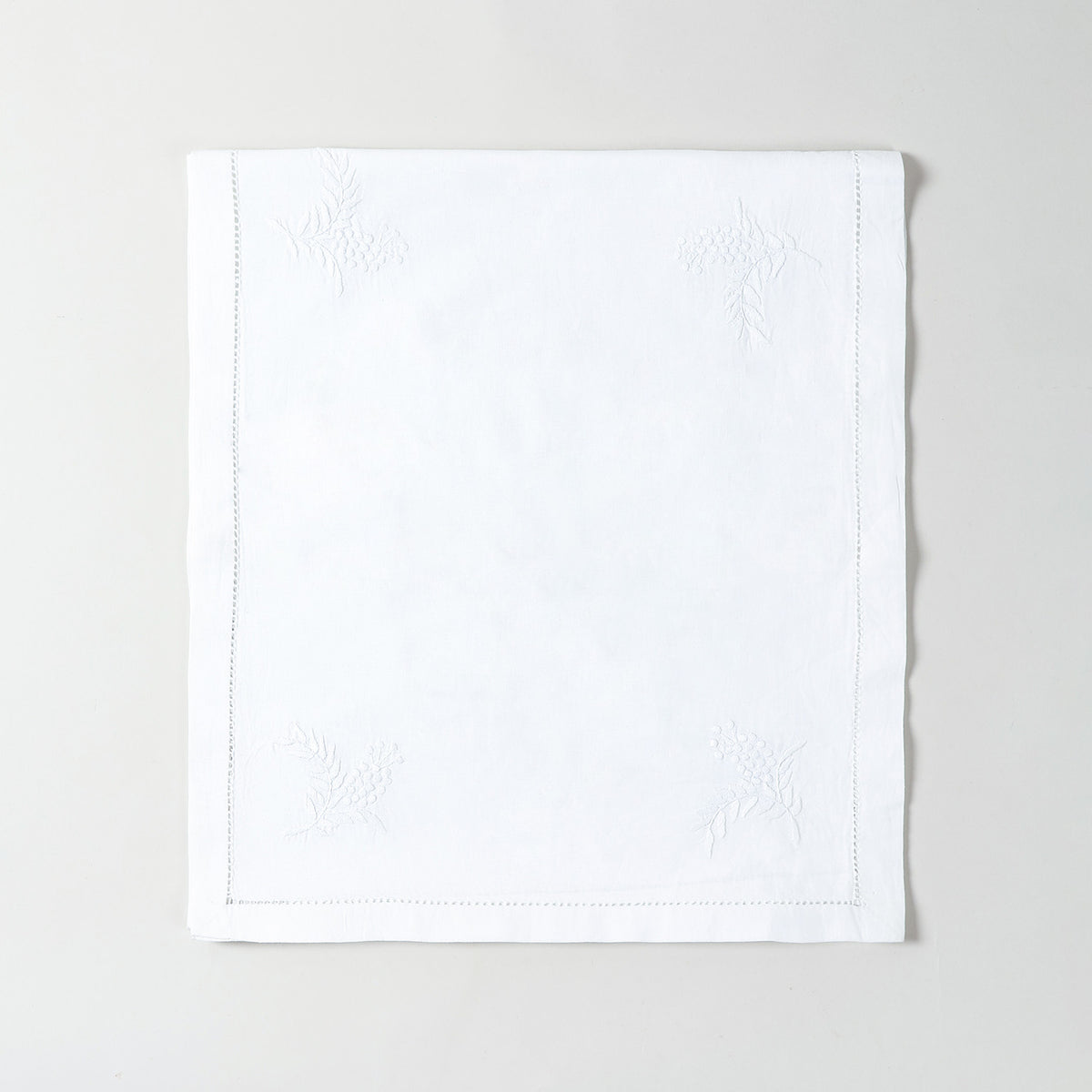 Folded white cotton table runner showcasing delicate chikankari wild floral embroidery and premium handmade craftsmanship