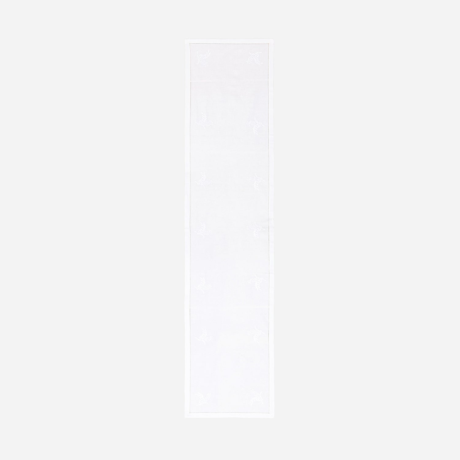 Full-length white embroidered table runner featuring hand-embroidered wild floral motifs on a white cotton base displayed on a plain background
