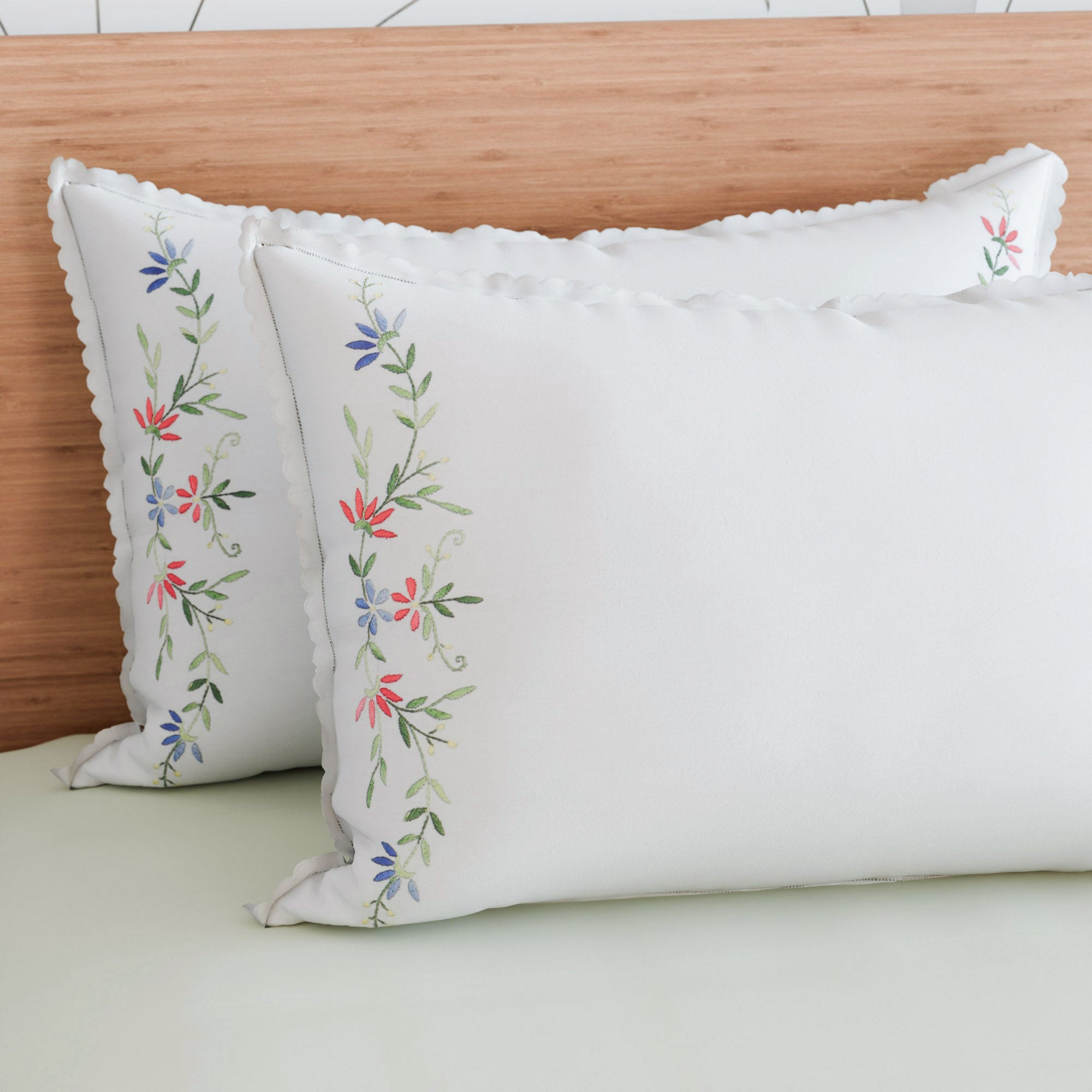Wild floral embroidered pillow cases styled on a bed bringing colour and handcrafted touch to bedroom decor
