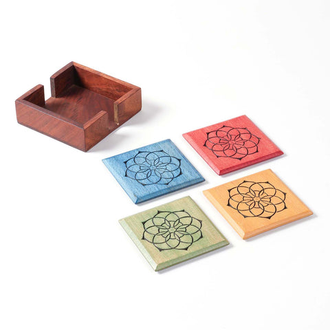 Angled view of a wooden coaster holder with four handcrafted Mandala wooden coasters placed beside it.