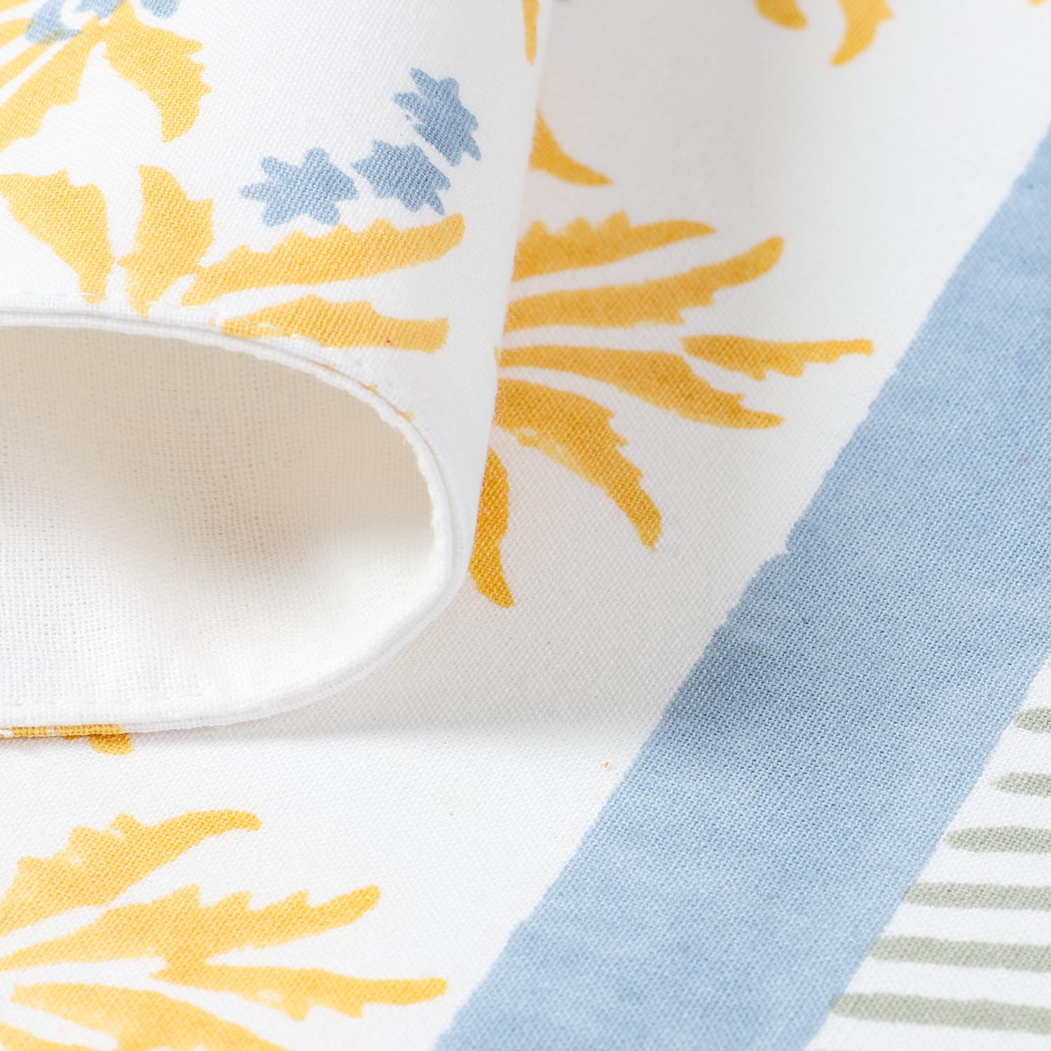 Close view of yellow floral motifs and blue stripe accents on handcrafted cotton table placemat