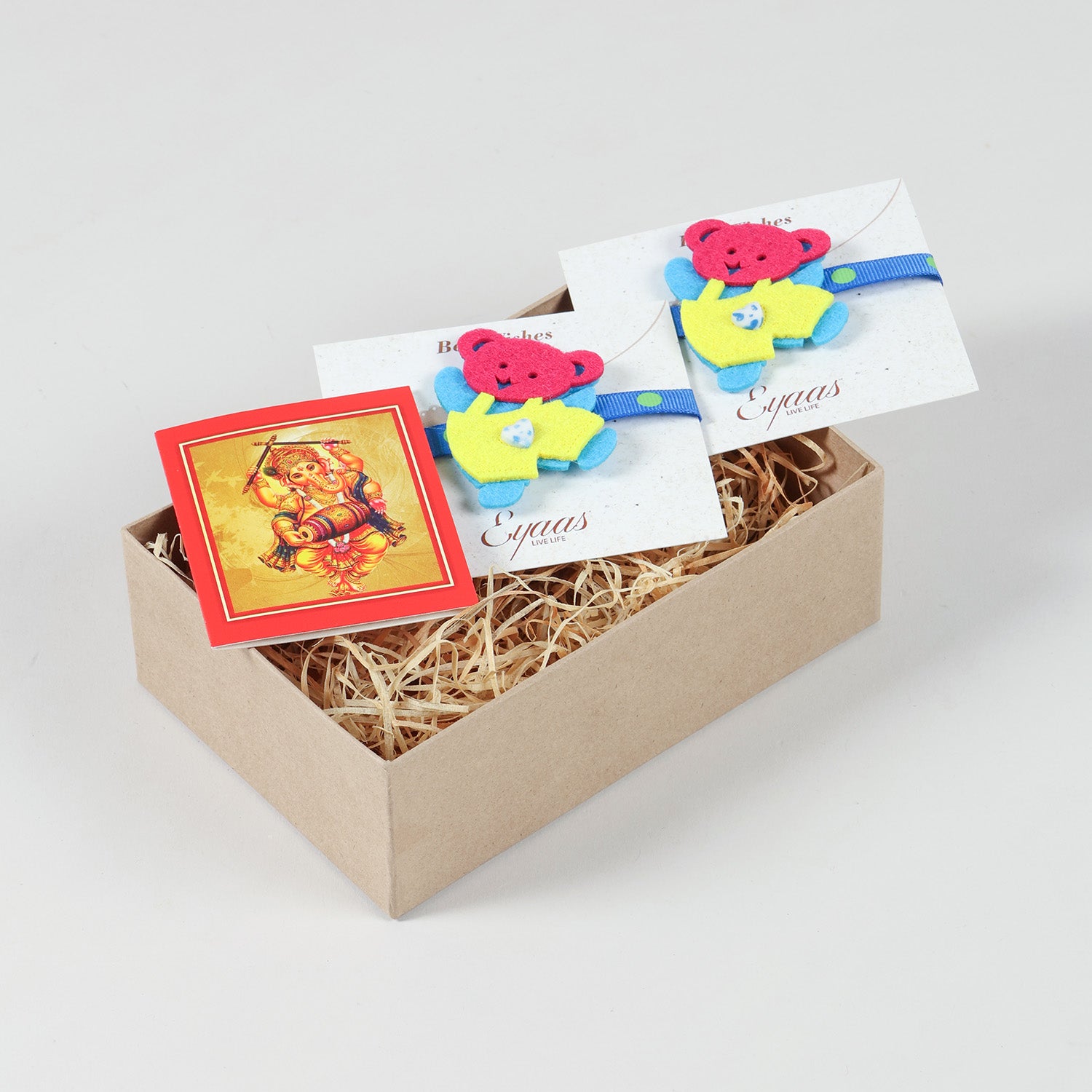 Open gift box featuring the handmade Blue and Yellow Teddy Bear Felt Kids Rakhi, ready for festive gifting.