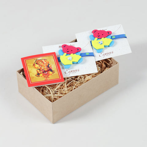 Open gift box featuring the handmade Blue and Yellow Teddy Bear Felt Kids Rakhi, ready for festive gifting.