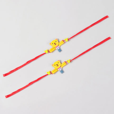 Full-length view of the yellow Cartoon Teddy Bear Wooden Kids Rakhi Set of 2, showing the complete red ribbon band and handcrafted teddy design.