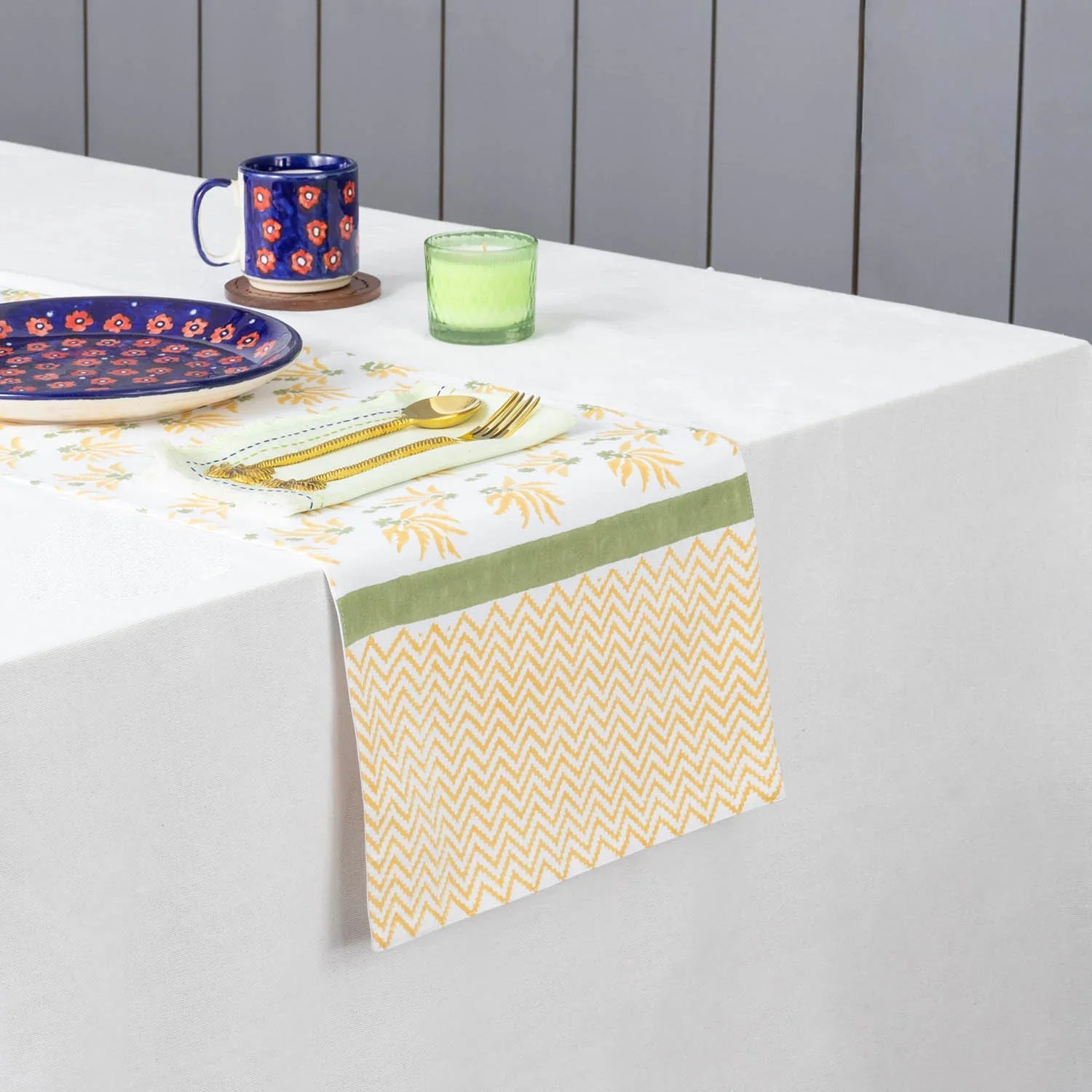 Yellow floral hand block printed cotton table runner styled on a dining table with coordinated tableware and decor accents