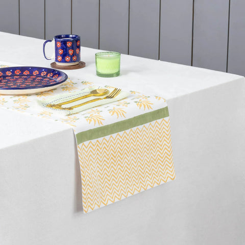 Yellow floral hand block printed cotton table runner styled on a dining table with coordinated tableware and decor accents