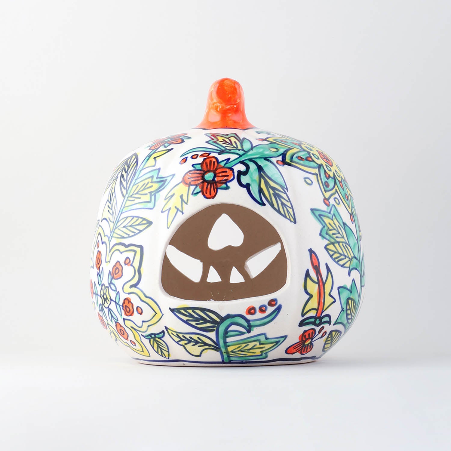 Back view of a hand painted yellow floral ceramic pumpkin tea light holder showcasing a wide cutout designed to easily place a tea light or candle