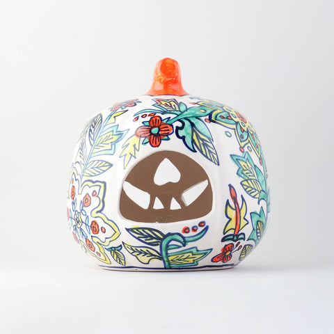 Back view of a hand painted yellow floral ceramic pumpkin tea light holder showcasing a wide cutout designed to easily place a tea light or candle