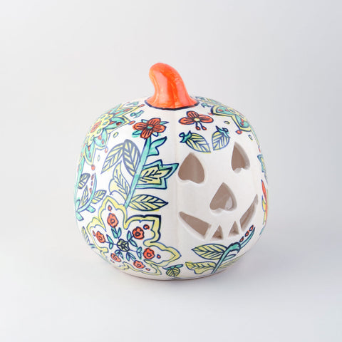 Side view of a hand-painted ceramic pumpkin t-light holder with decorative cutwork and floral patterns