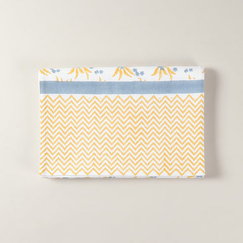 Folded cotton table runner featuring yellow and blue floral motifs with handcrafted block printed design