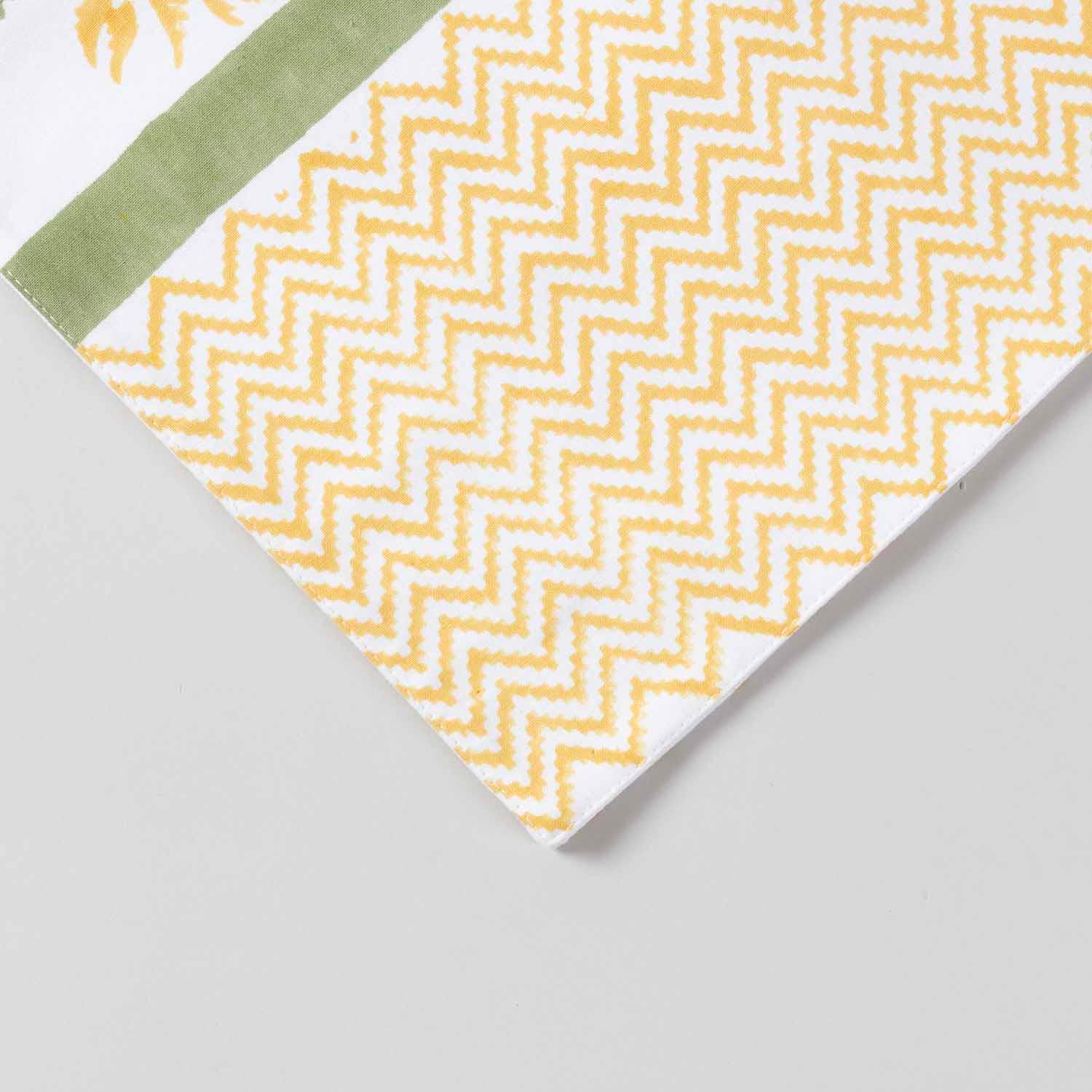 Close-up corner view of a yellow floral hand-block printed cotton table runner with zigzag patterned border