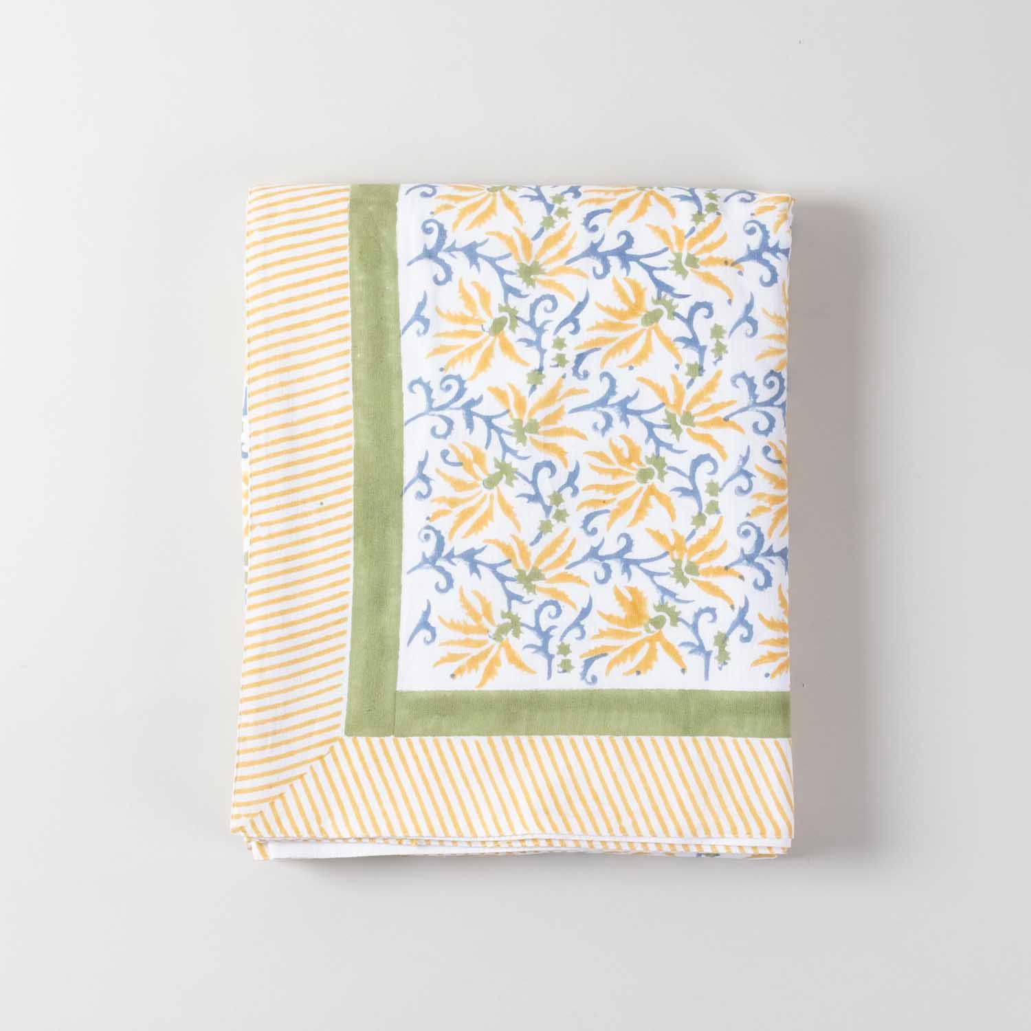 Folded yellow lily block printed cotton table cover showcasing handcrafted floral patterns and cotton texture
