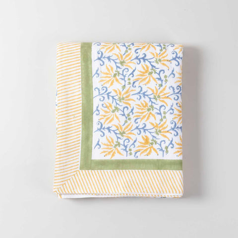 Folded yellow lily block printed cotton table cover showcasing handcrafted floral patterns and cotton texture