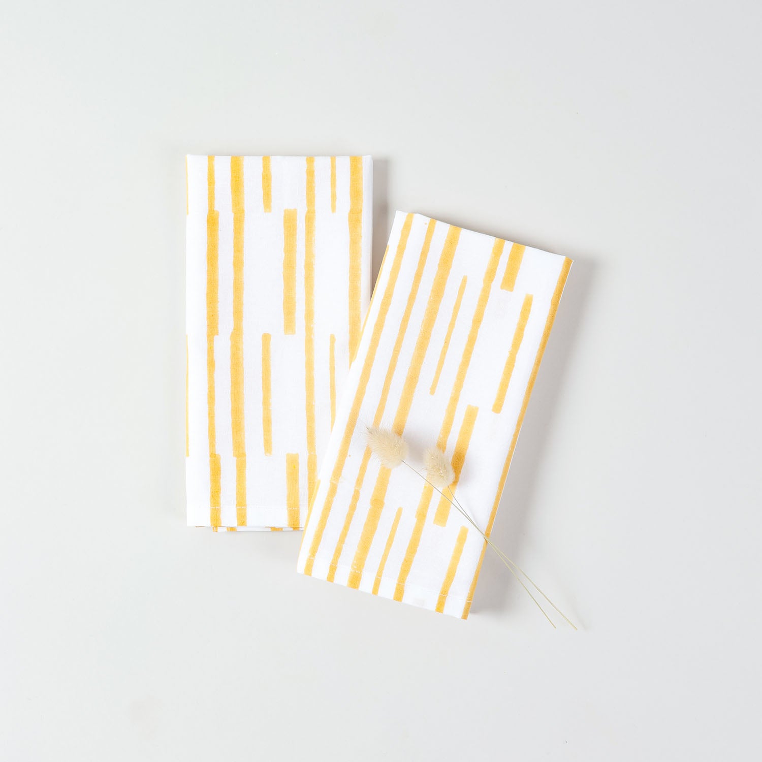 Yellow stripe cotton napkins displayed with natural dried grass accents for seasonal table styling