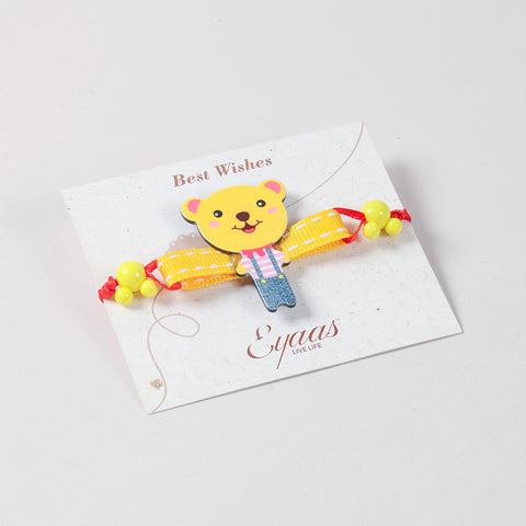 Angled view of the yellow Teddy Bear Wooden Kids Rakhi Set of 2 attached to a festive Best Wishes card, ready for Raksha Bandhan gifting