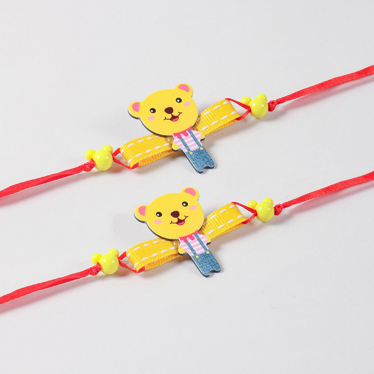Close-up of the handmade yellow Teddy Bear Wooden Kids Rakhi Set of 2, highlighting the wooden teddy design and red ribbon details.