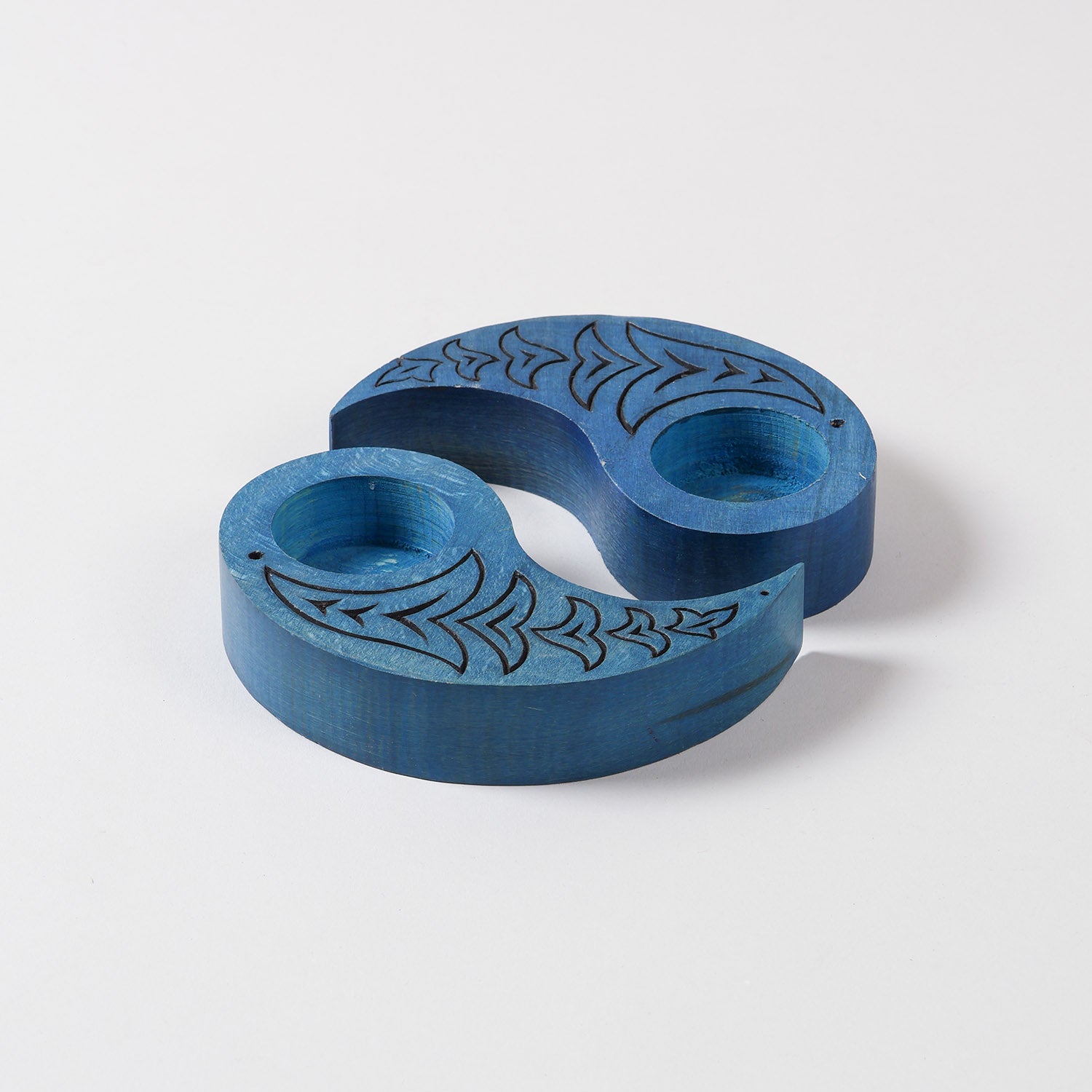 Angled view of hand carved wooden T-light holders in blue, featuring bird motifs and a Ying Yang shape, perfect for decorative candle holder displays