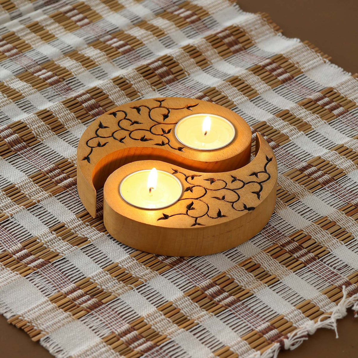 Hand-carved wooden Ying Yang leaves T-light holders set of 2 in yellow, displayed with lit tea lights on a woven table linen, ideal for handmade decor and Diwali deco