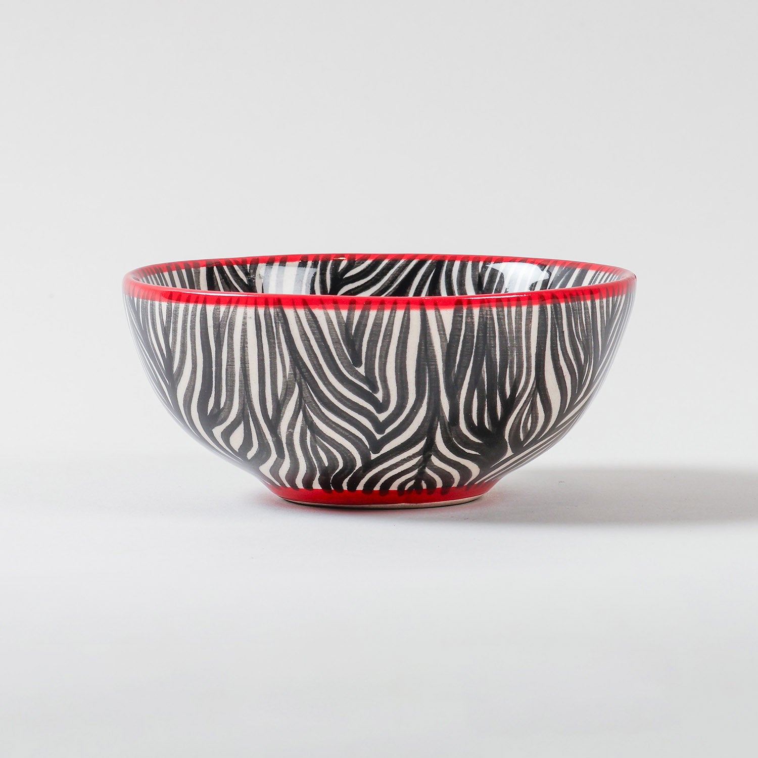 Handmade African ceramic bowl featuring a zebra stripe pattern and contrasting rim, suitable as a snack bowl, salad bowl, or decorative tableware piece